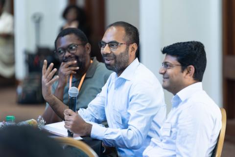 three postdoc scholars talking, one holds microphone
