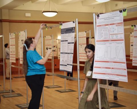 two postdocs stand with posters