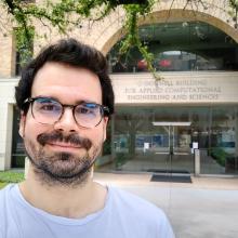 A person poses in front of the entrance to UT Austin's O'Donnell Building for Applied Computational Engineering and Sciences.