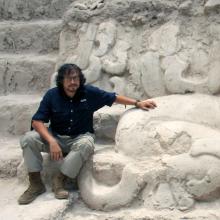 A person sits on a stone monument.