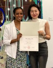 YeonHa Ju poses with her teaching certificate in front of a mural standing next to Lydia Contreras.