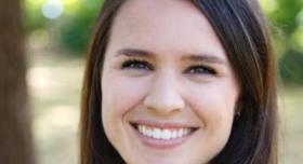 A person stands outdoors for a headshot.