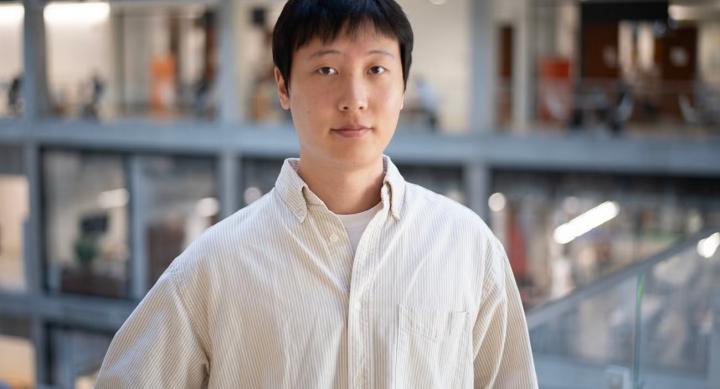 A person in a white shirt poses indoors.