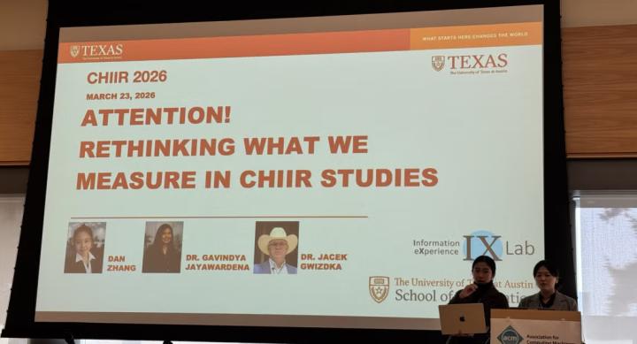 Two researchers present a PowerPoint presentation titled "Attention! Rethinking What We Measure in CHIIR Studies."