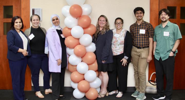 postdocs standing next to each other with a balloon arch